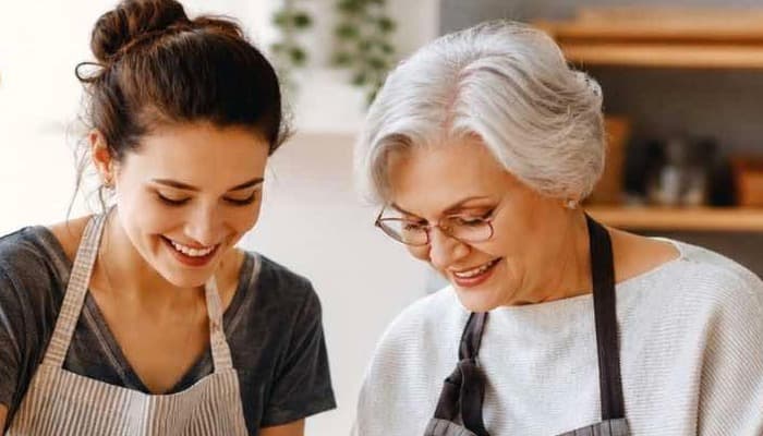 Companion and older adult cooking together